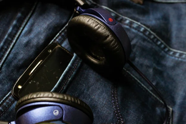 Headphones and a black phone in the back pocket of jeans. Copy S — Stock Photo, Image