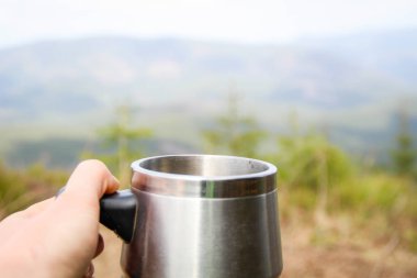 Dağlara bakan elinde kupa. Bir piknik ve bir yürüyüş t