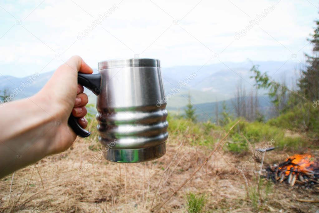 Cup in the hand overlooking the mountains. A picnic and a hike t