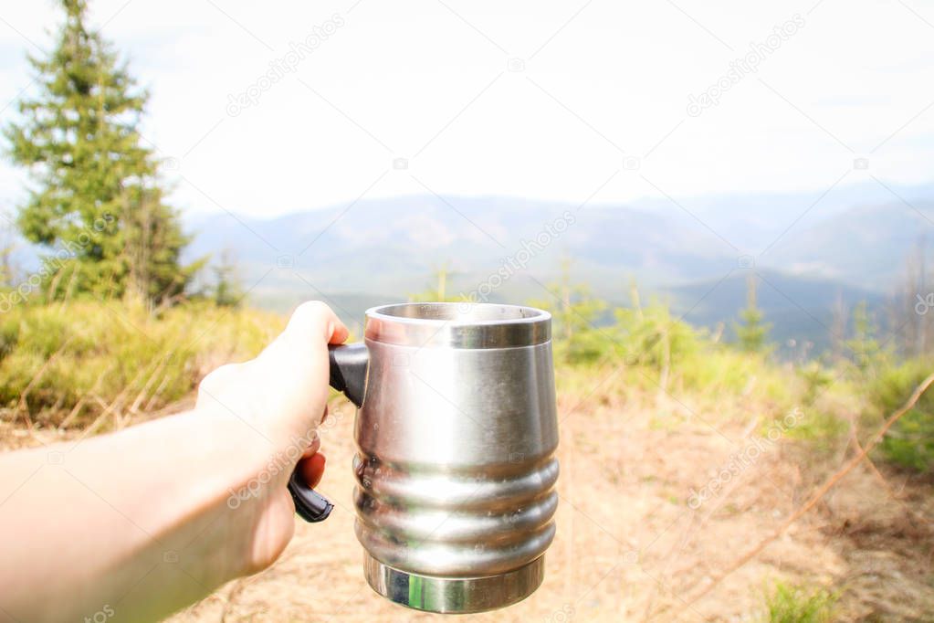 Cup in the hand overlooking the mountains. A picnic and a hike t