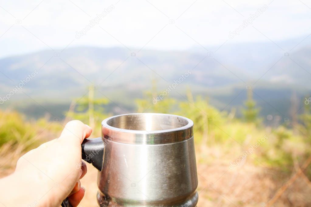 Cup in the hand overlooking the mountains. A picnic and a hike t