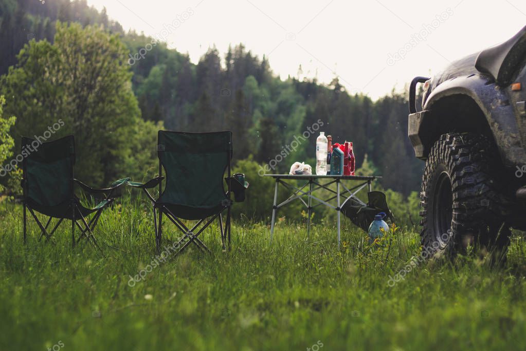 Picnic in the mountains with folding chairs and a table. The car