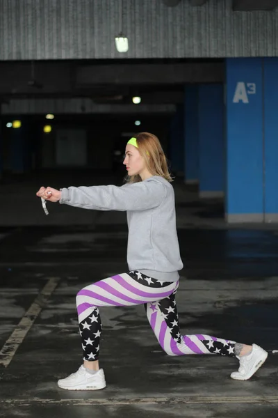 Chica es una entrenadora rubia en una delgada gris. Estilo callejero. Advertisi — Foto de Stock