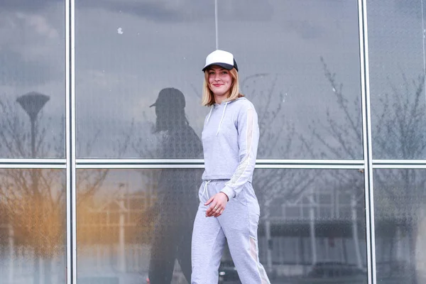 La chica es rubia con un traje deportivo gris. Ropa de calle. Deporte — Foto de Stock