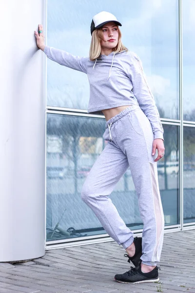 La chica es rubia con un traje deportivo gris. Ropa de calle. Deporte — Foto de Stock