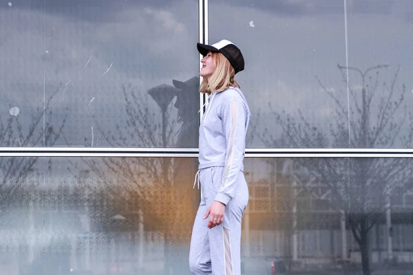 La chica es rubia con un traje deportivo gris. Ropa de calle. Deporte — Foto de Stock