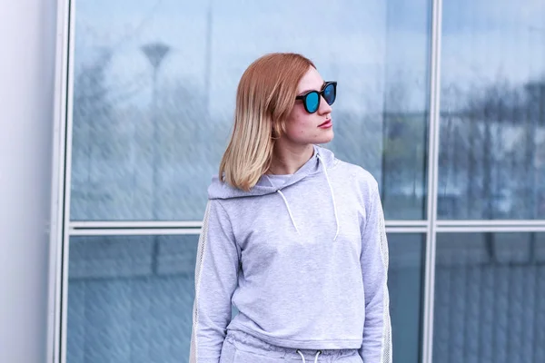 La chica es rubia con un traje deportivo gris. Ropa de calle. Deporte —  Fotos de Stock