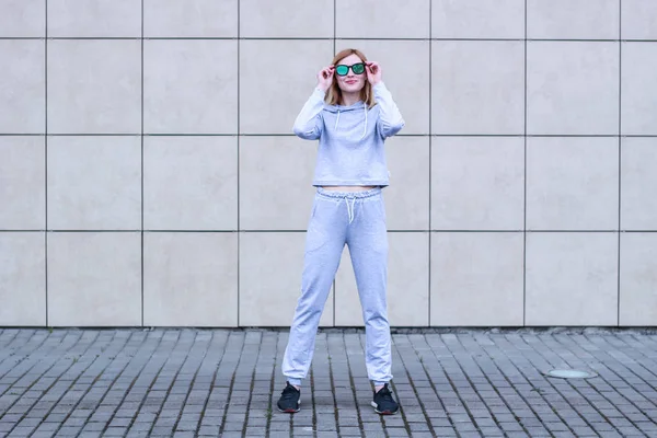 La chica es rubia con un traje deportivo gris. Ropa de calle. Deporte — Foto de Stock