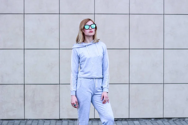 La chica es rubia con un traje deportivo gris. Ropa de calle. Deporte — Foto de Stock