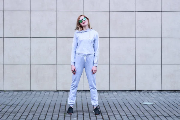 La chica es rubia con un traje deportivo gris. Ropa de calle. Deporte — Foto de Stock