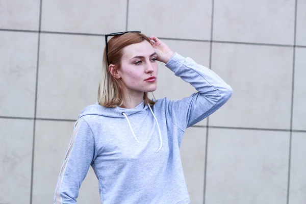 La chica es rubia con un traje deportivo gris. Ropa de calle. Deporte — Foto de Stock