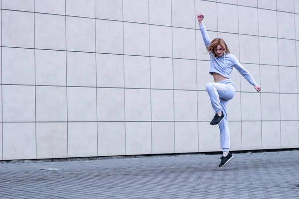 La fille est blonde en costume de sport gris. Des vêtements de ville. Le sport — Photo