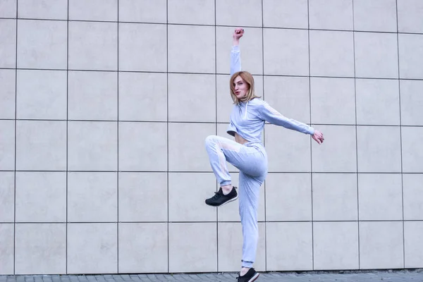 La fille est blonde en costume de sport gris. Des vêtements de ville. Le sport — Photo