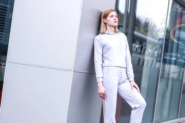 La chica es rubia con un traje deportivo gris. Ropa de calle. Deporte — Foto de Stock