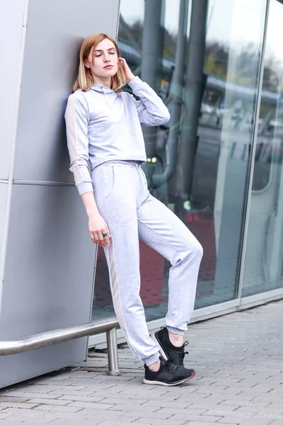 La chica es rubia con un traje deportivo gris. Ropa de calle. Deporte — Foto de Stock