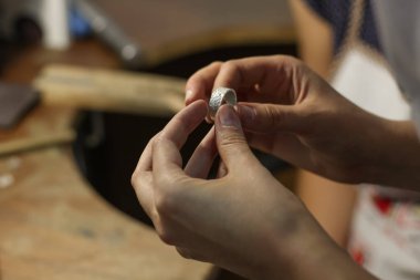 Bir mücevher ustası gümüş bir yüzük oluşturmak için çalışıyor