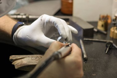 Bir mücevher ustası gümüş bir yüzük oluşturmak için çalışıyor