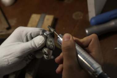 Bir mücevher ustası gümüş bir yüzük oluşturmak için çalışıyor