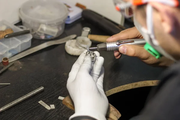 A jewelry master is working to create a silver ring