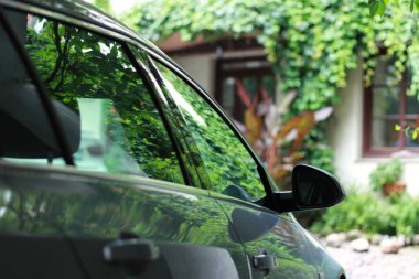 Evin bahçesinde araba. Yeşil. Arabada parıldama. Ayna.