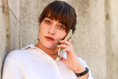 İş kadını telefonda konuşuyordu. İşe yarıyor. Moda. Beyaz gömlek, siyah ceket ve etek. Eski binanın arka planı.