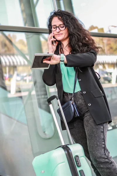 Black-haired girl traveling with luggage. Business woman goes on