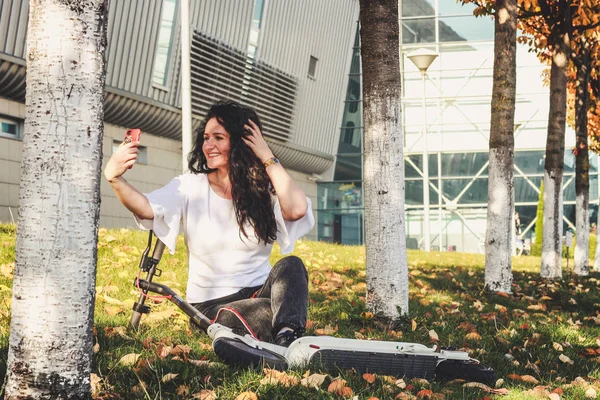 Chica de pelo negro. En un scooter eléctrico. Otoño. Descanse en la l — Foto de Stock