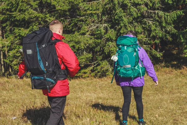 Miúda e homem caminhantes nas montanhas. Mochilas de viagem e roupas . — Fotografia de Stock