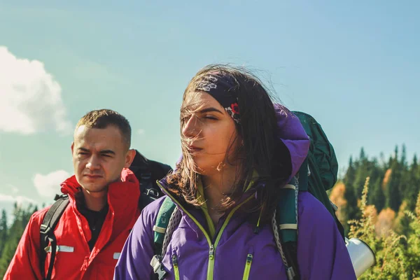 Dağlarda kız ve erkek yürüyüşçüler. Seyahat çantaları ve giysileri. — Stok fotoğraf