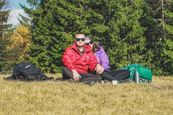 Girl and man hikers in mountains. They drink tea and coffee on t — Stock Photo, Image