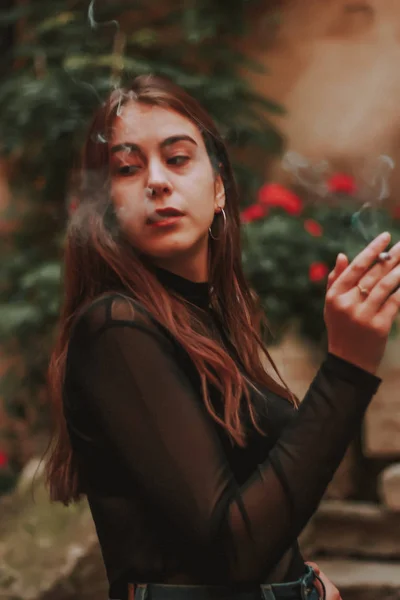 Κομψό κορίτσι καπνίζει ένα τσιγάρο. Καπνός. Σμόγκ. Μαύρο κομψό γκολφ — Φωτογραφία Αρχείου