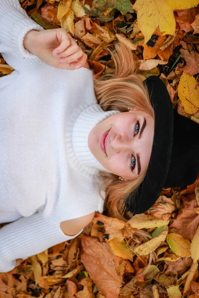 Herfst meisje portretten. Model in witte trui ligt op gele lea — Stockfoto