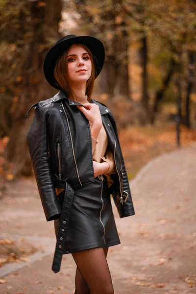 Stylová podzimní dívka v parku. Svetr, klobouk a kožená bunda — Stock fotografie