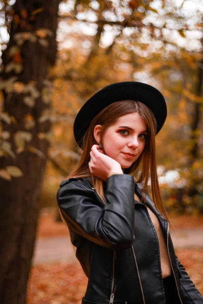 Menina de outono elegante no parque. Camisola, chapéu e casaco de couro — Fotografia de Stock