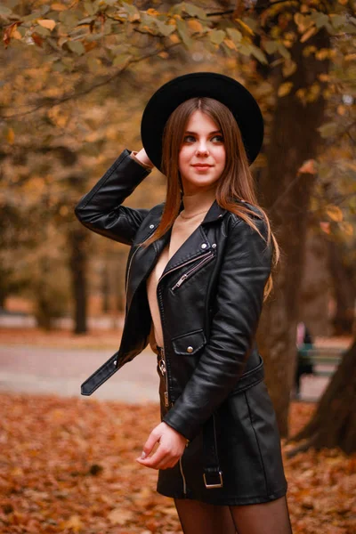 Menina de outono elegante no parque. Camisola, chapéu e casaco de couro — Fotografia de Stock