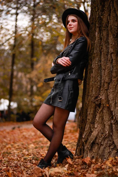 Stijlvol herfstmeisje in het park. Trui, hoed en leren jas — Stockfoto
