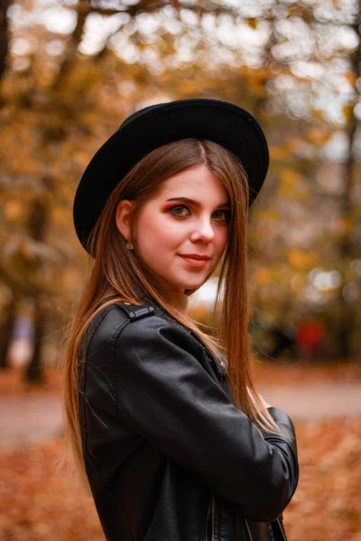 Menina de outono elegante no parque. Camisola, chapéu e casaco de couro — Fotografia de Stock