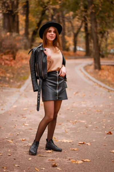 Menina de outono elegante no parque. Camisola, chapéu e casaco de couro — Fotografia de Stock