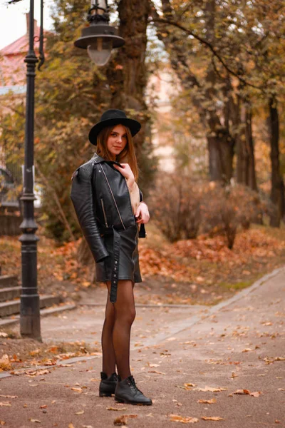 Stylowa jesienna dziewczyna w parku. Sweter, kapelusz i skórzana kurtka — Zdjęcie stockowe