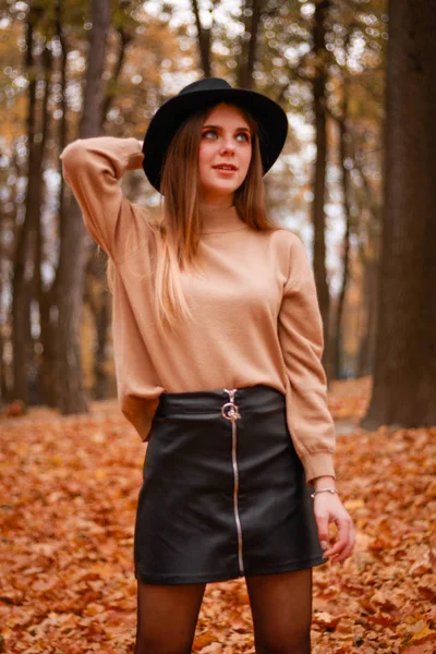 Podzimní dívka v parku. Svetr, klobouk a koženou sukni. Stylový — Stock fotografie