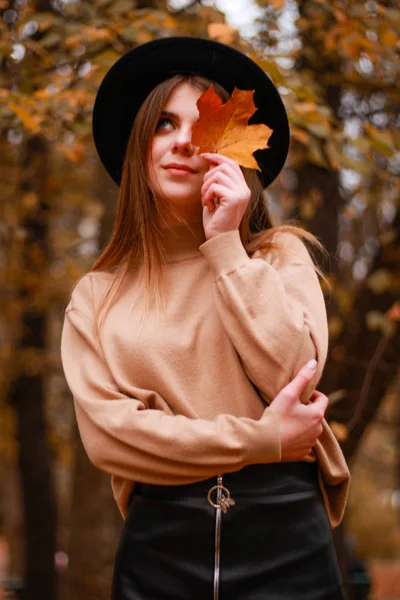 Rapariga de outono no parque. Camisola, chapéu e saia de couro. Elegante — Fotografia de Stock