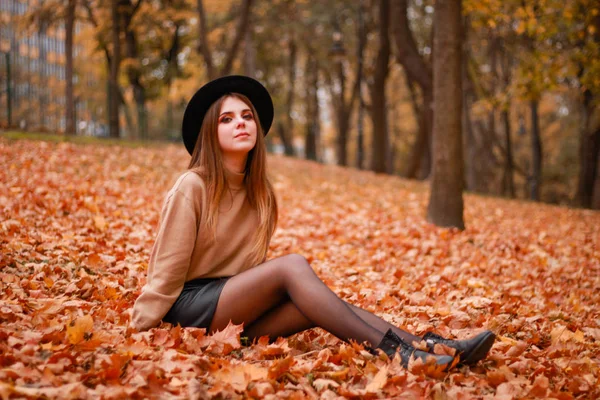 Jesienna dziewczyna w parku. Sweter, kapelusz i skórzana spódnica. Stylowe — Zdjęcie stockowe