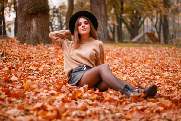 Höstflickan i parken. Tröja, hatt och läderkjol. Snygg — Stockfoto