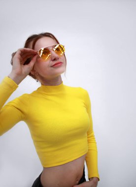 Tarz sahibi bir kızın portresi. Bej gözlükler. 2020 ilkbahar ve yaz trendi. Siyah şort ve sarı bluz.. 