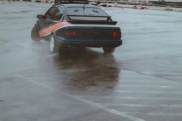 車は古い駐車場で漂流している 雨のドリフト 灰色の写真処理 雰囲気 市内でのレース — ストック写真