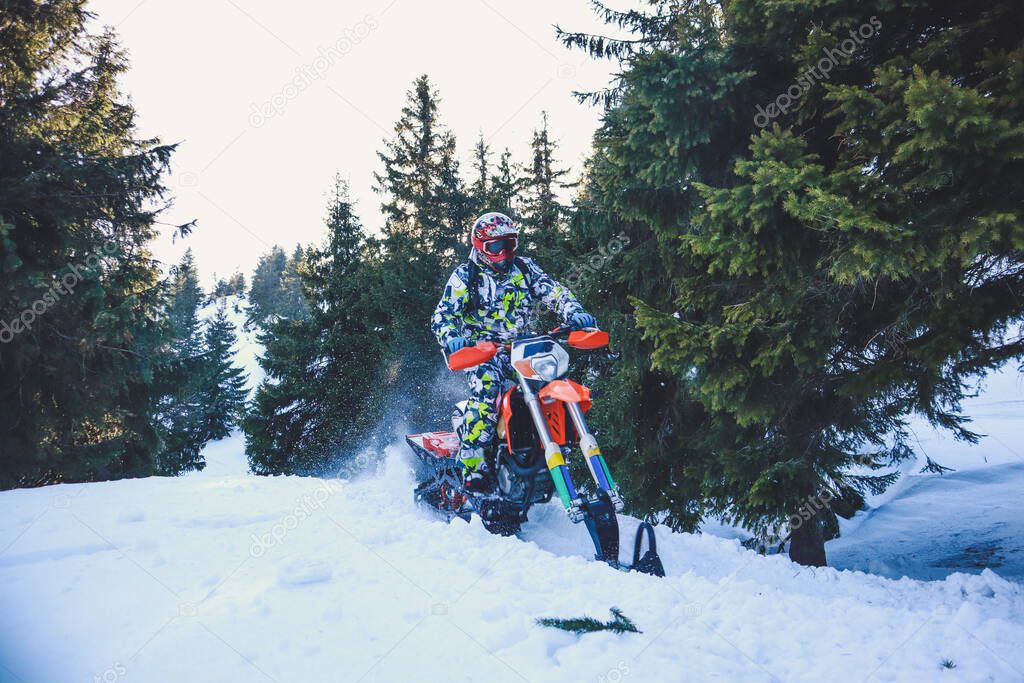 Snowbike rider in mountain valley in beautiful snow powder. Snowdirt bike with splashes and trail. Snowmobile winter sport riding