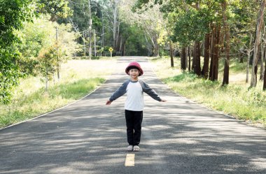 Küçük Asyalı çocuk parkta yolun ortasında duran