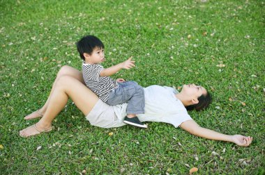 İşaret ve annesi parkta oturan küçük Asya çocuk