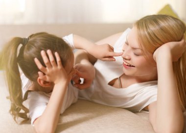 Annem ve onun sevimli kız çocuk, gülümseyerek ve sarılma oynuyorlar. Mutlu anneler günü. Aile tatili ve beraberlik