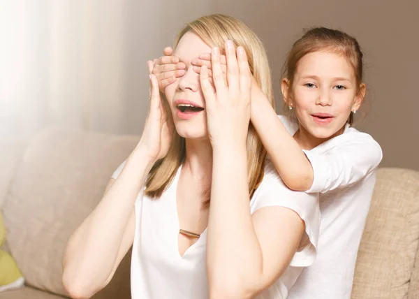 Young girl is closing her mother eyes. Beautiful mother and her little daughter are smiling. People happiness, leisure, family and motherhood concept — Stock Photo, Image